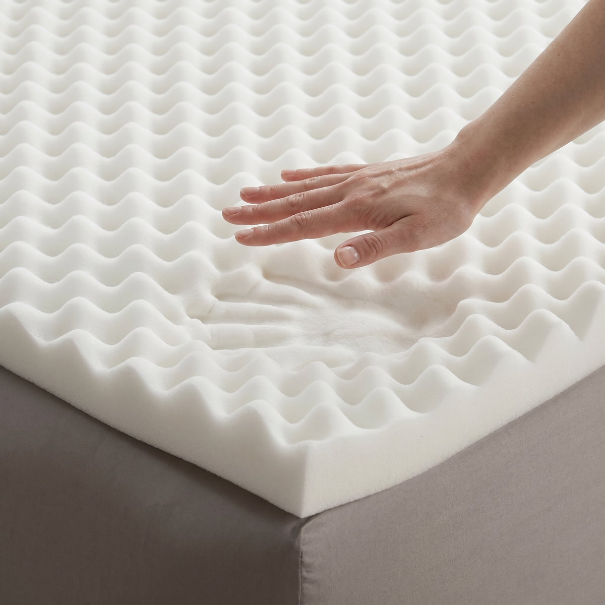 Hand pressing the profiled surface of a foam mattress topper