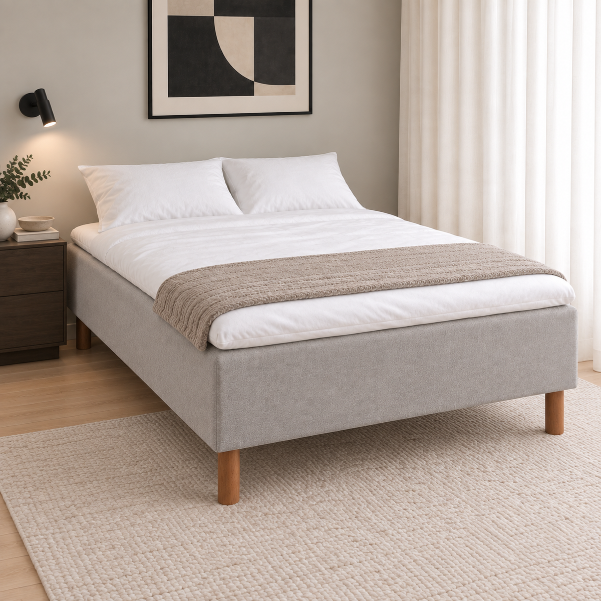 Light grey upholstered bed on wooden legs with white bedding and a beige throw.
