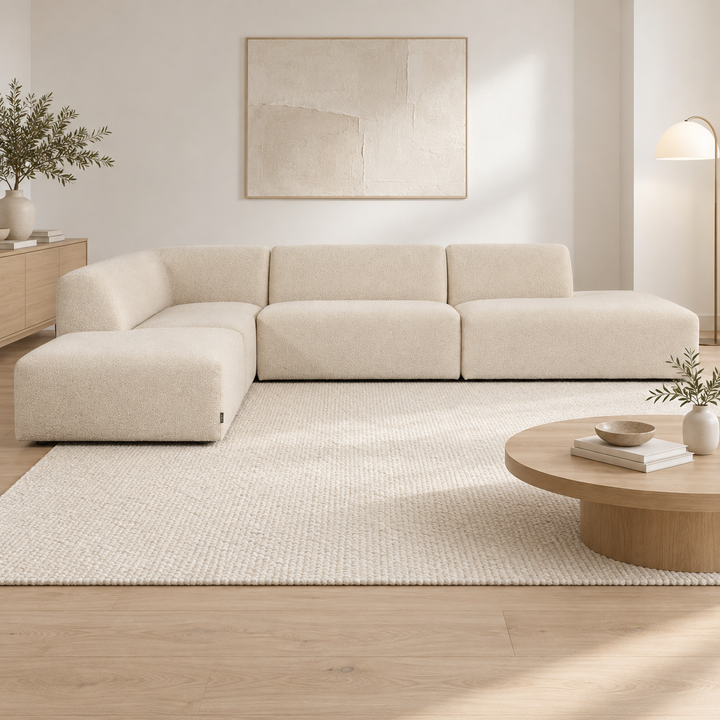 Ljusbeige Heta-hörnsoffa med divan till vänster och öppet avslut till höger, intill ett runt träbord.