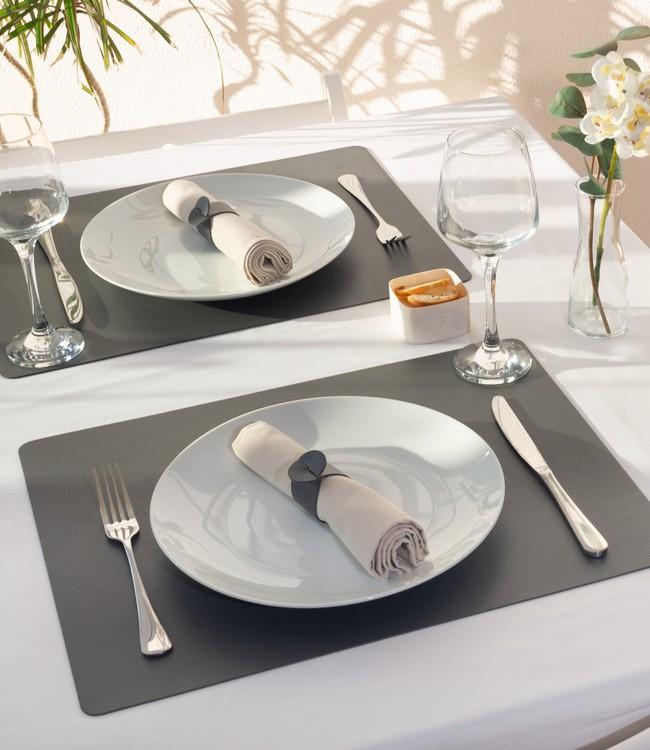 Finesse placemats in dark grey beneath white plates and cloth napkins on a set table