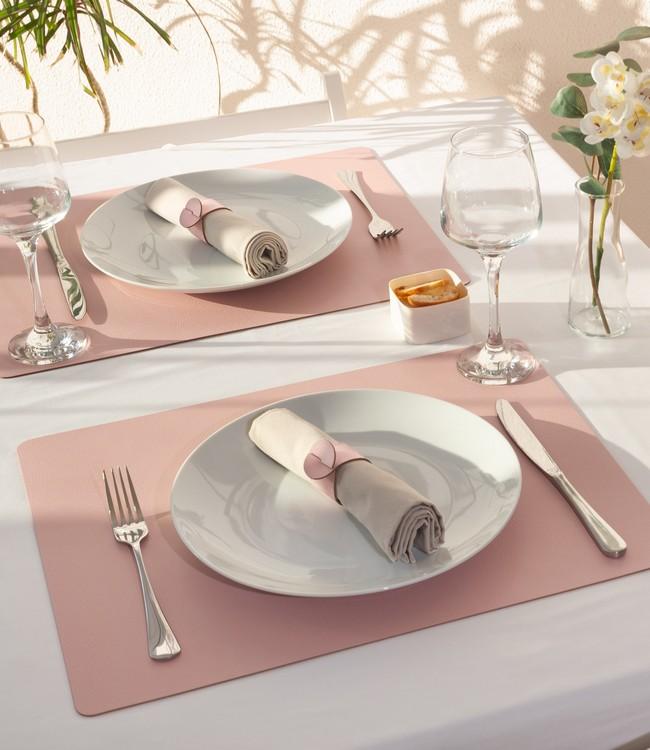 Finesse placemats in pink beneath white plates and cloth napkins on a set table