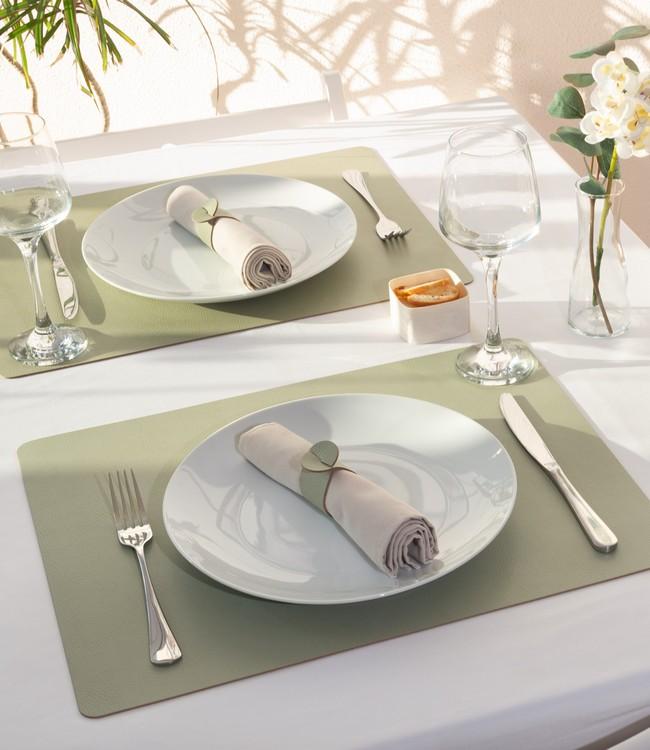 Finesse placemats in green beneath white plates and cloth napkins on a set table