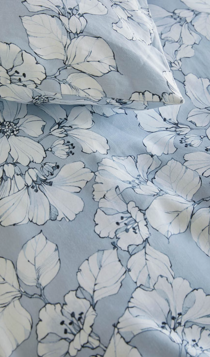 Close-up of large white leaves on the blue background of Høie Amelia bedding