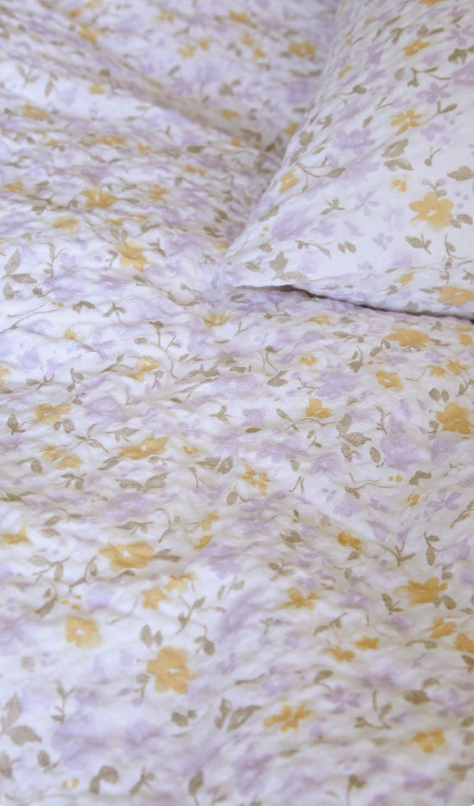 Närbild av små lavendelfärgade och gula blommor på Høie Clara-sängkläder