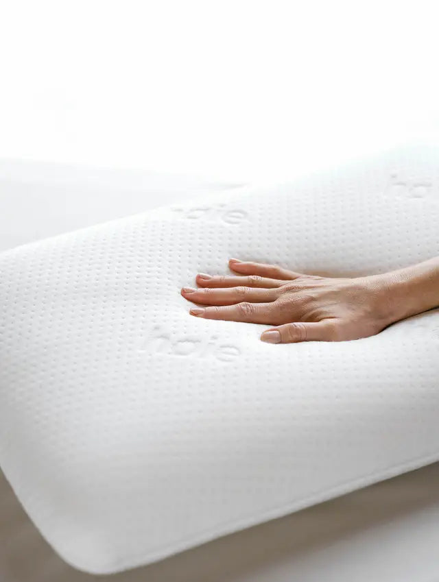 Hand pressing the surface of a white Høie Classic Memoryfoam pillow