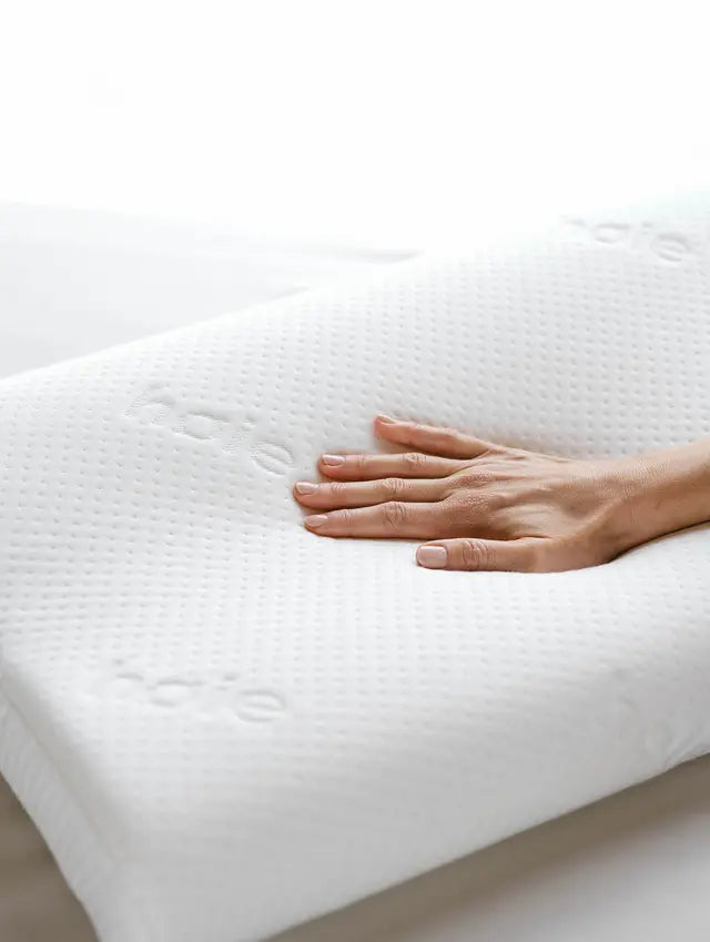 Käsi painaa valkoisen Høie Contour Memoryfoam -tyynyn pintaa
