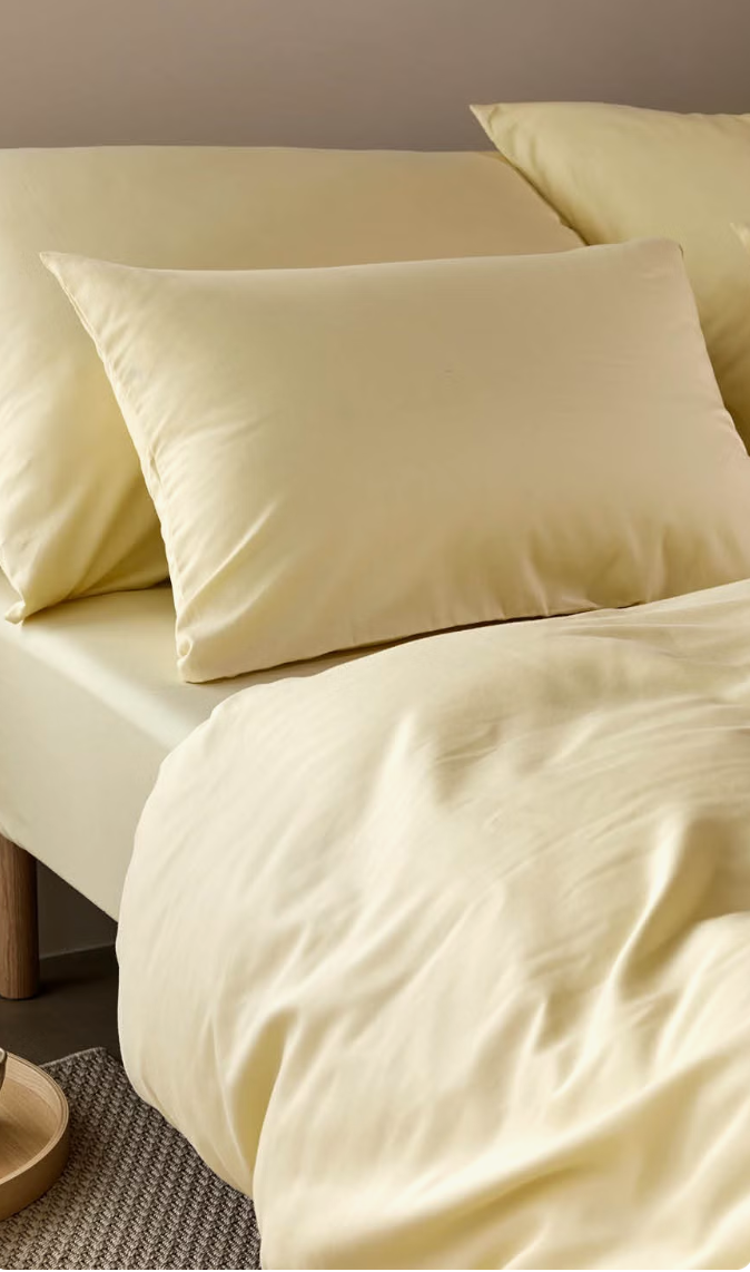 Close view of Høie Harmoni bedding on a bed with a yellow duvet cover and upright pillows