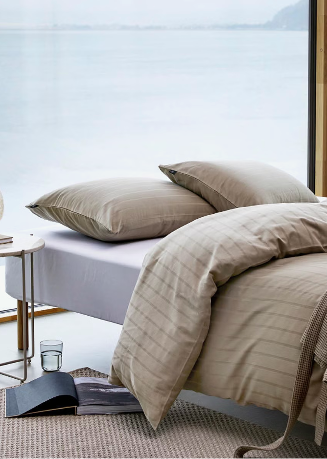 Light brown Høie Milano duvet cover set on a made bed in a bedroom; subtle tonal stripes