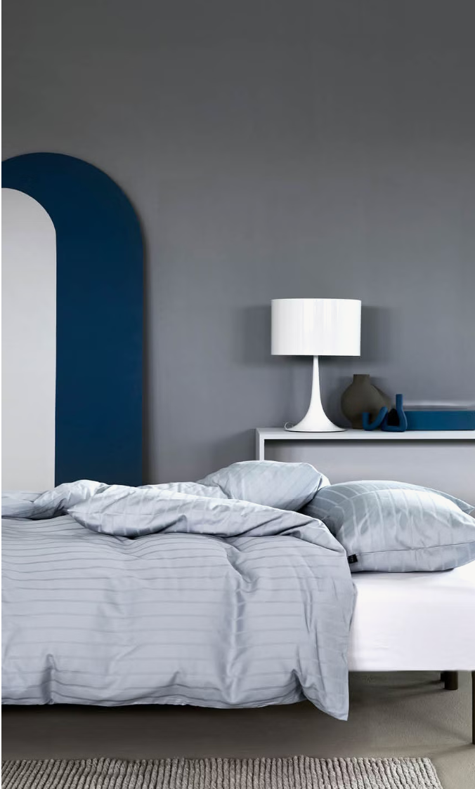 Light blue Høie Milano duvet cover set on a made bed in a bedroom; subtle tonal stripes