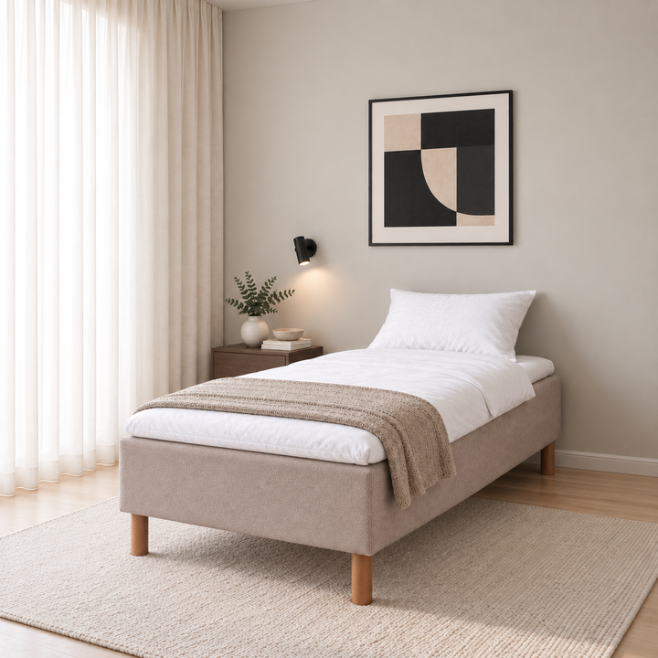 Hotel Basic Pocket runkosänky 100x200 cm, Thomas 03 beige, vaaleassa makuuhuoneessa viistosti jalkopäästä kuvattuna. Sisustushavainnekuva; Hotel Plus -petauspatja sisältyy hintaan, vuodevaatteet eivät.