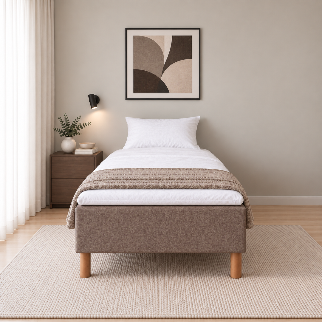 Hotel Basic Pocket runkosänky 120x200 cm, Sawana 25 ruskea modernissa makuuhuoneessa suoraan jalkopäästä kuvattuna. Sisustushavainnekuva; Hotel Plus -petauspatja sisältyy hintaan, vuodevaatteet eivät.