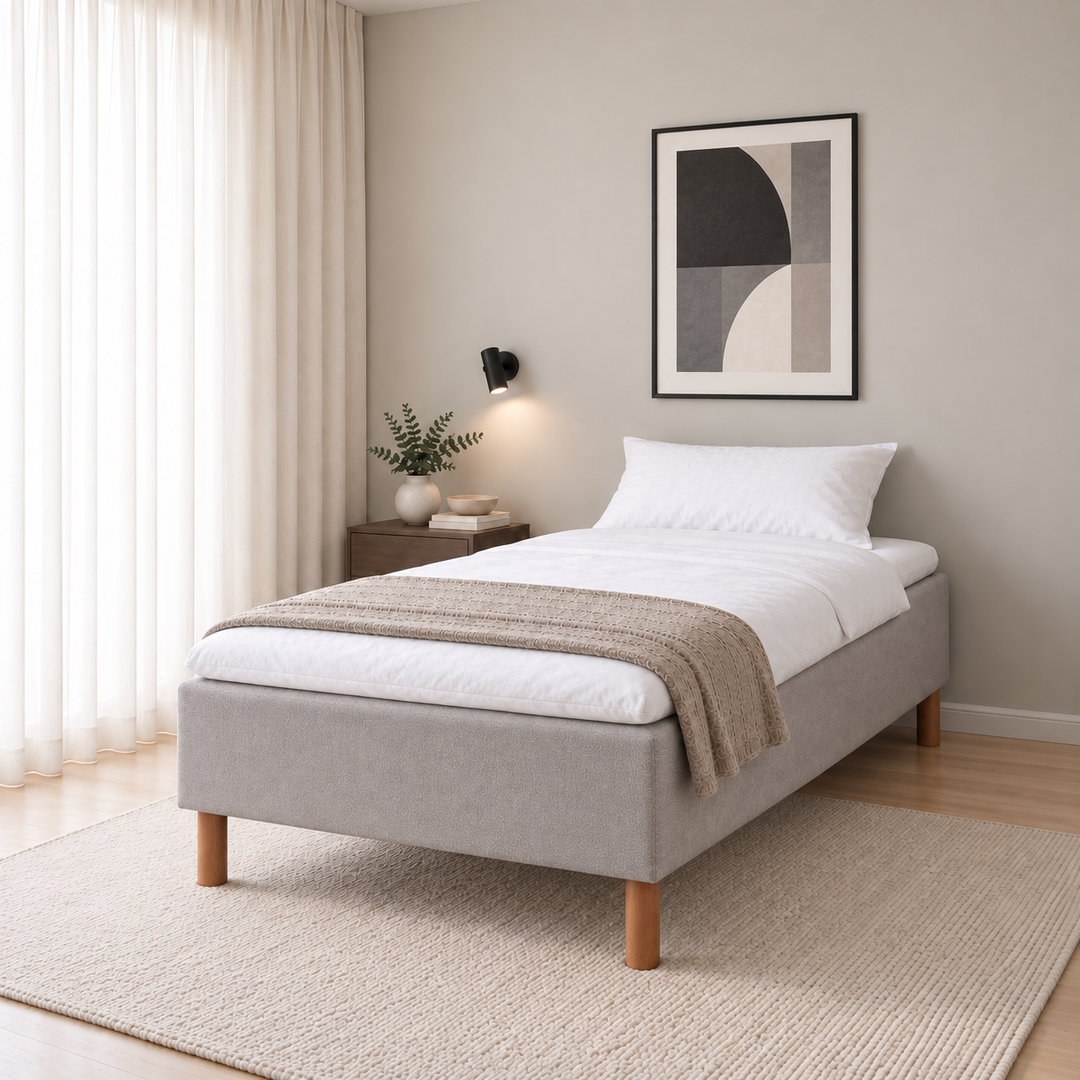 Hotel Basic Pocket runkosänky 120x200 cm, Vogue 14 vaaleanharmaa modernissa makuuhuoneessa viistosti jalkopäästä kuvattuna. Sisustushavainnekuva; Hotel Plus -petauspatja sisältyy hintaan, vuodevaatteet eivät.
