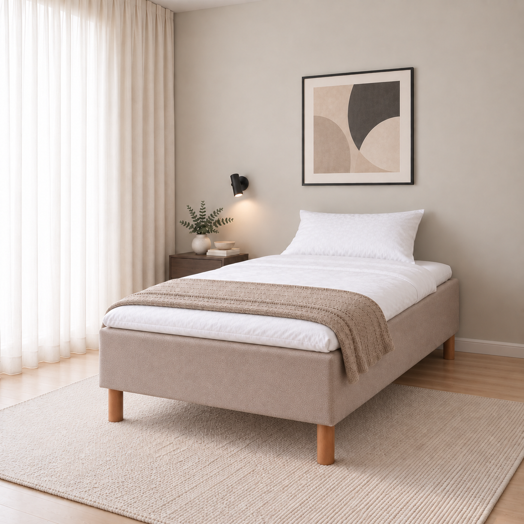 Hotel Basic Pocket runkosänky 140x200 cm, Thomas 03 beige modernissa makuuhuoneessa, viistosta kuvattuna. Yksi tyyny. Sisustushavainnekuva; Hotel Plus -petauspatja sisältyy hintaan, vuodevaatteet eivät.