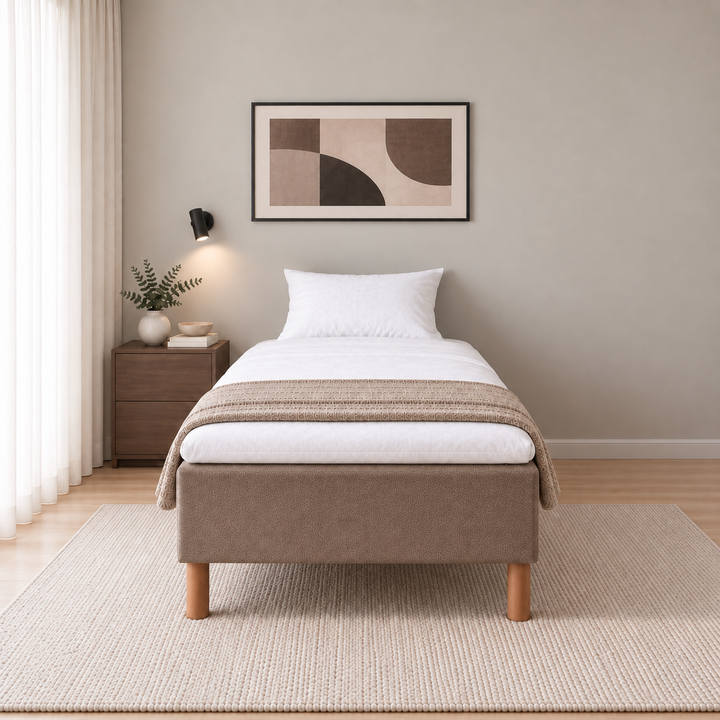 Front view of a brown upholstered single bed with wooden legs, white bedding and a knitted throw in a light bedroom. Interior visualisation.