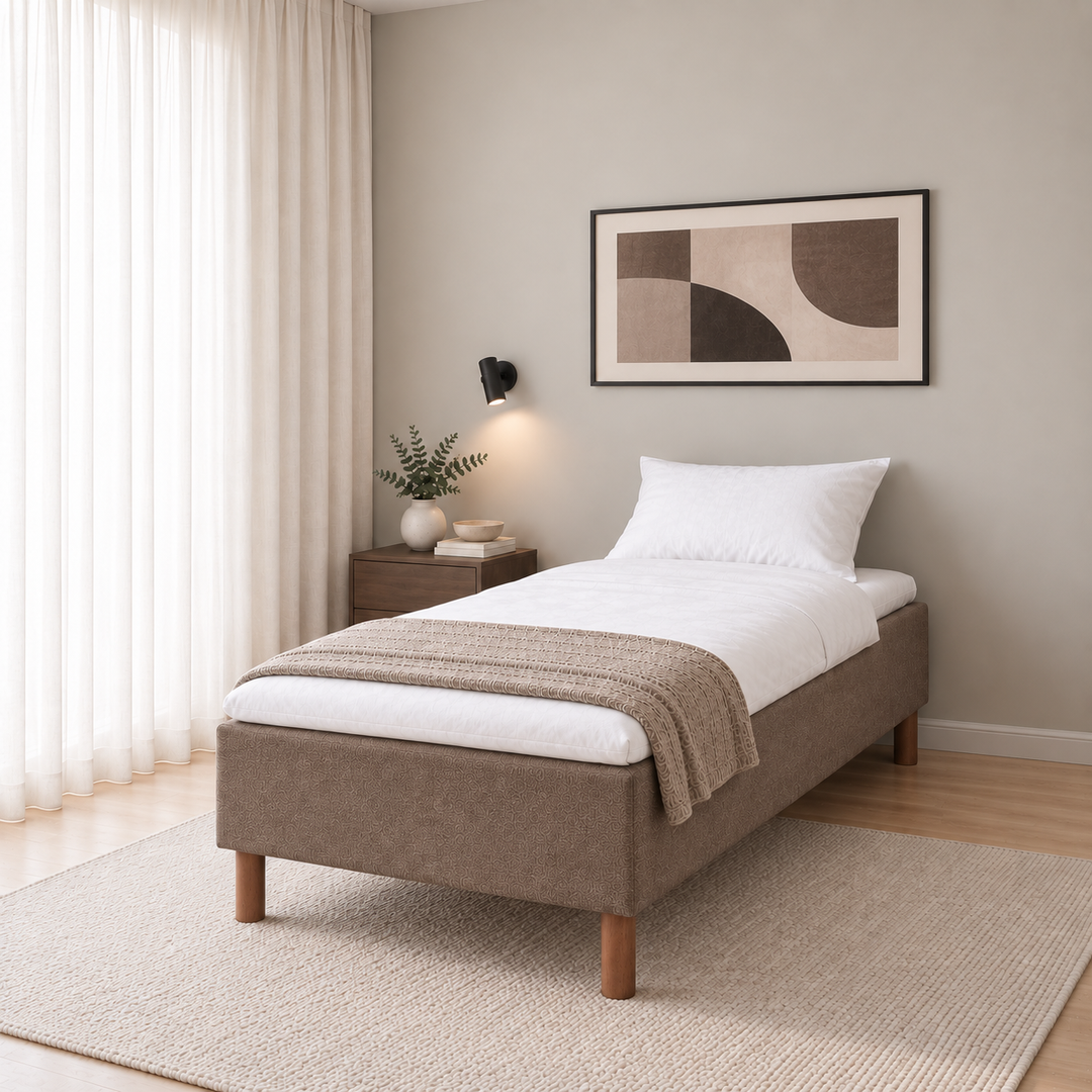 Hotel Basic Pocket runkosänky 80x200 cm, Sawana 25 ruskea modernissa makuuhuoneessa viistosti jalkopäästä kuvattuna. Sisustushavainnekuva; Hotel Plus -petauspatja sisältyy hintaan, vuodevaatteet eivät.