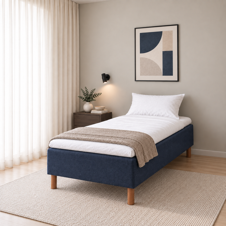Hotel Basic Pocket runkosänky 80x200 cm, Sawana 80 sininen modernissa makuuhuoneessa viistosti jalkopäästä kuvattuna. Sisustushavainnekuva; Hotel Plus -petauspatja sisältyy hintaan, vuodevaatteet eivät.
