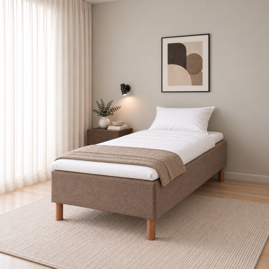 Hotel Basic Pocket runkosänky 90x200 cm, Sawana 25 ruskea modernissa makuuhuoneessa viistosti jalkopäästä kuvattuna. Sisustushavainnekuva; Hotel Plus -petauspatja sisältyy hintaan, vuodevaatteet eivät.