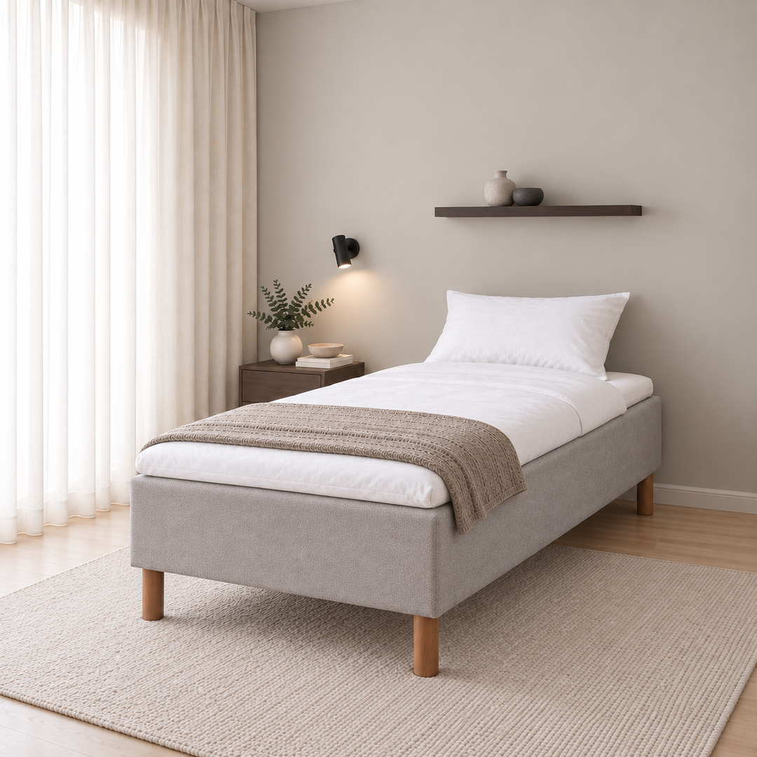 Hotel Basic Pocket runkopatja, No Problem 90x200 cm, Vogue 14 vaaleanharmaa modernissa makuuhuoneessa viistosti jalkopäästä kuvattuna. Sisustushavainnekuva; petauspatja ja vuodevaatteet eivät sisälly runkopatjaan.