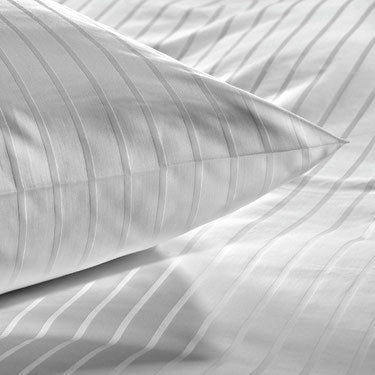 Valkoisten Hotel Innsbruck -vuodevaatteiden satiiniraidat lähikuvassa