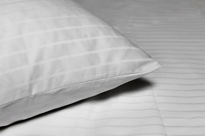 Valkoisen Hotel Innsbruck -tyynyliinan satiiniraidat ja kulma lähikuvassa