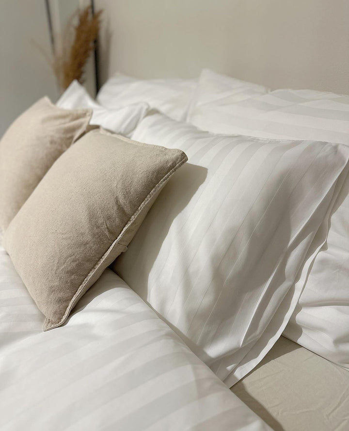 Valkoiset tyynyt ja pienempi beige koristetyyny lähikuvassa
