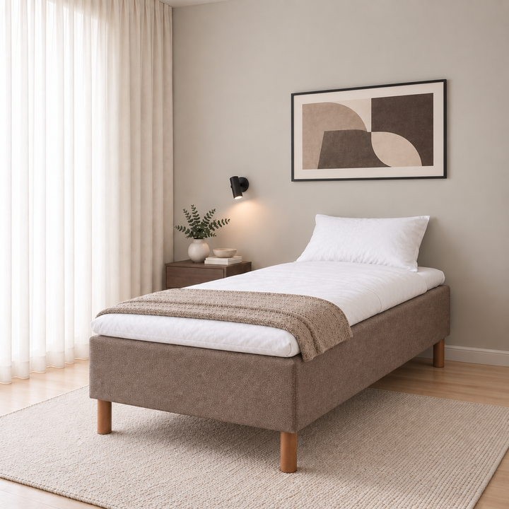 Hotel Luxus Pocket Bonnel runkosänky 100x200 cm, Sawana 25 ruskea modernissa makuuhuoneessa viistosti jalkopäästä kuvattuna. Sisustushavainnekuva; Hotel Plus -petauspatja sisältyy hintaan, vuodevaatteet eivät.