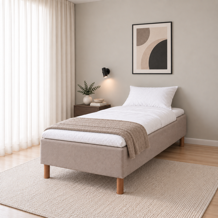 Hotel Luxus Pocket Bonnel runkosänky 100x200 cm, Thomas 03 beige modernissa makuuhuoneessa viistosti jalkopäästä kuvattuna. Sisustushavainnekuva; Hotel Plus -petauspatja sisältyy hintaan, vuodevaatteet eivät.