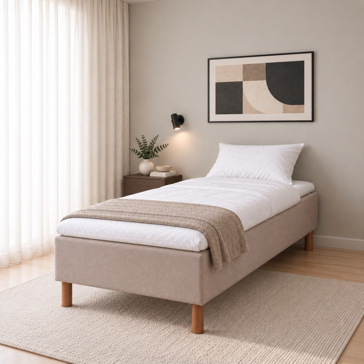 Hotel Luxus Pocket Bonnel runkosänky 105x200 cm, Thomas 03 beige modernissa makuuhuoneessa viistosti jalkopäästä kuvattuna. Sisustushavainnekuva; Hotel Plus -petauspatja sisältyy hintaan, vuodevaatteet eivät.