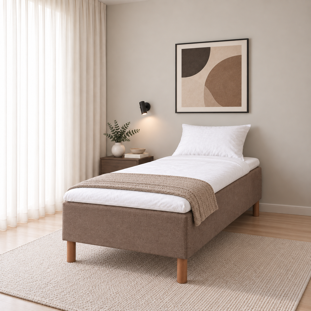 Hotel Luxus Pocket Bonnel runkosänky 80x200 cm, Sawana 25 ruskea modernissa makuuhuoneessa viistosti jalkopäästä kuvattuna. Sisustushavainnekuva; Hotel Plus -petauspatja sisältyy hintaan, vuodevaatteet eivät.