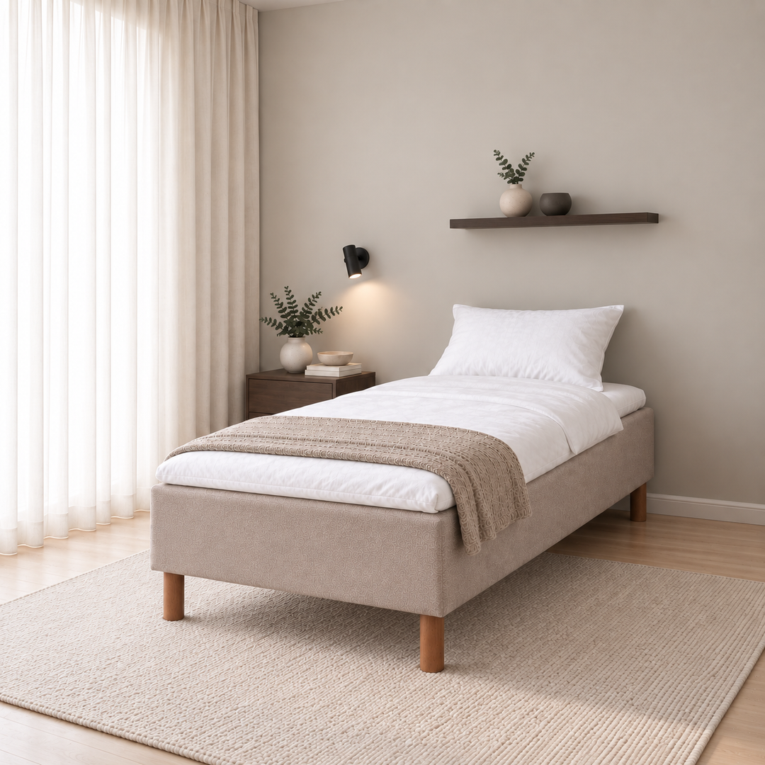 Hotel Luxus Pocket Bonnel runkosänky 80x200 cm, Thomas 03 beige modernissa makuuhuoneessa viistosti jalkopäästä kuvattuna. Sisustushavainnekuva; Hotel Plus -petauspatja sisältyy hintaan, vuodevaatteet eivät.