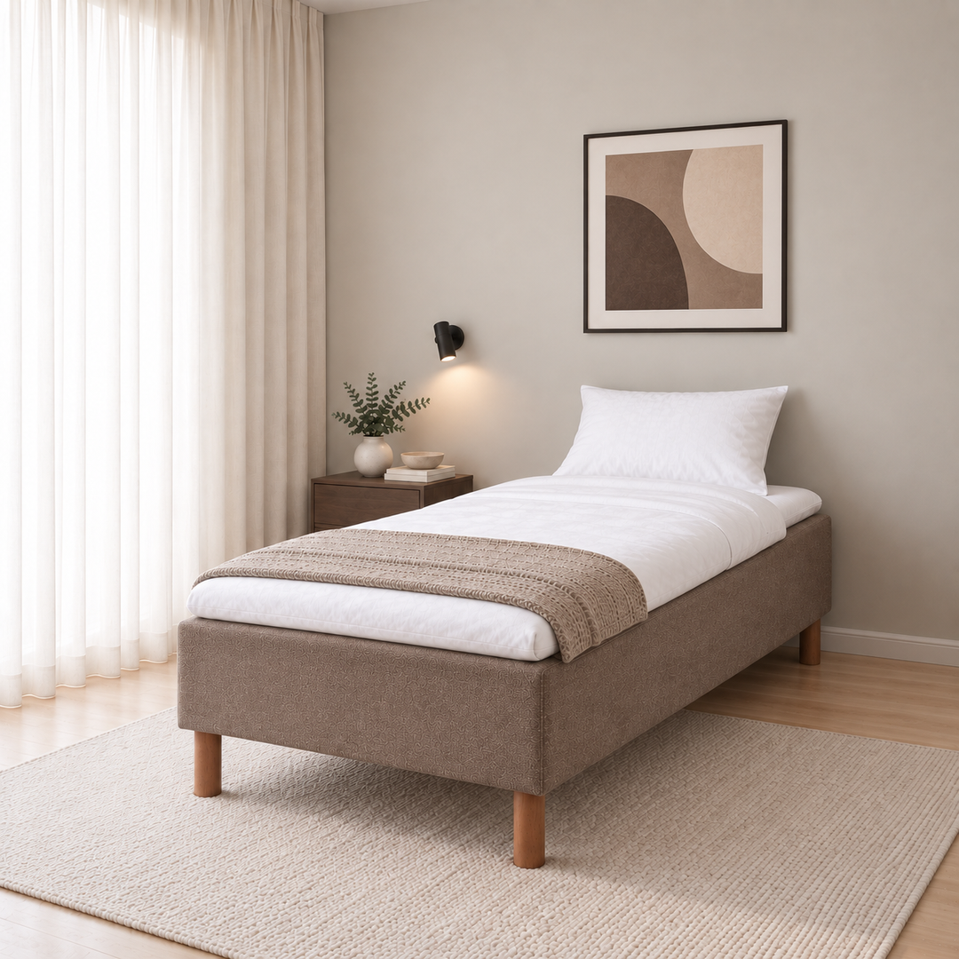 Hotel Luxus Pocket Bonnel runkosänky 90x200 cm, Sawana 25 ruskea modernissa makuuhuoneessa viistosti jalkopäästä kuvattuna. Sisustushavainnekuva; Hotel Plus -petauspatja sisältyy hintaan, vuodevaatteet eivät.