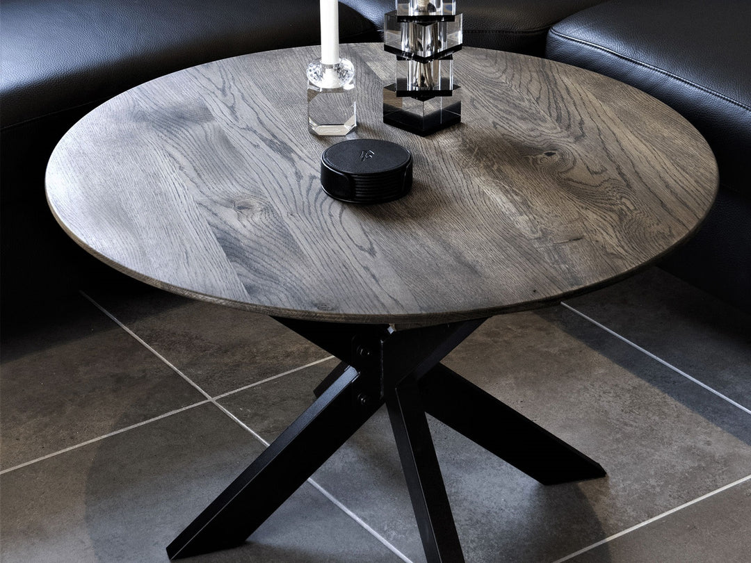 Tumma pyöreä sohvapöytä mustalla Opus Coffee Table -jalustalla mustan sohvan edessä