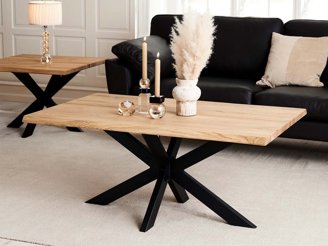 Vaalea puinen sohvapöytä mustalla Star Sofa Base -jalustalla mustan sohvan edessä