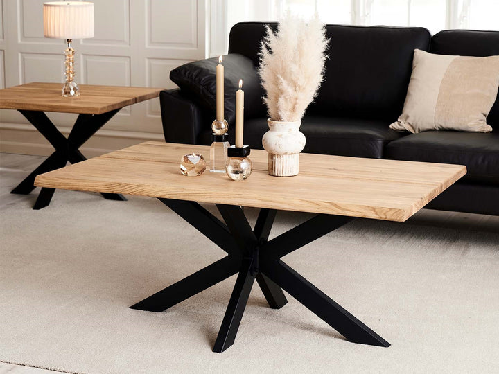 Vaalea puinen sohvapöytä mustalla Star Sofa Base -jalustalla mustan sohvan edessä