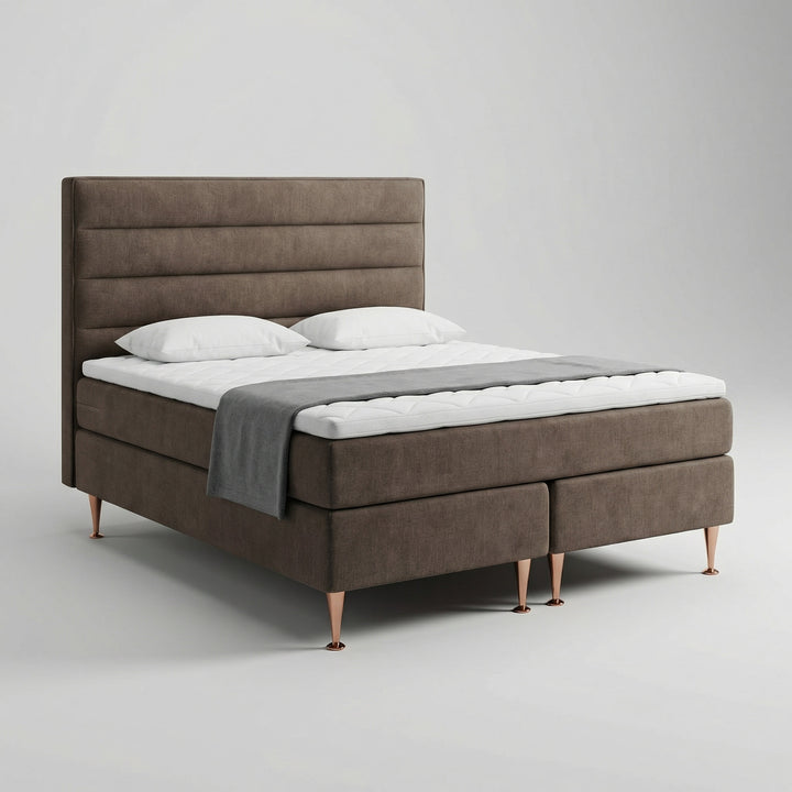 Brown No Problem Hotel Luxus 3 continental bed at an angle with a white mattress topper and horizontally padded headboard
