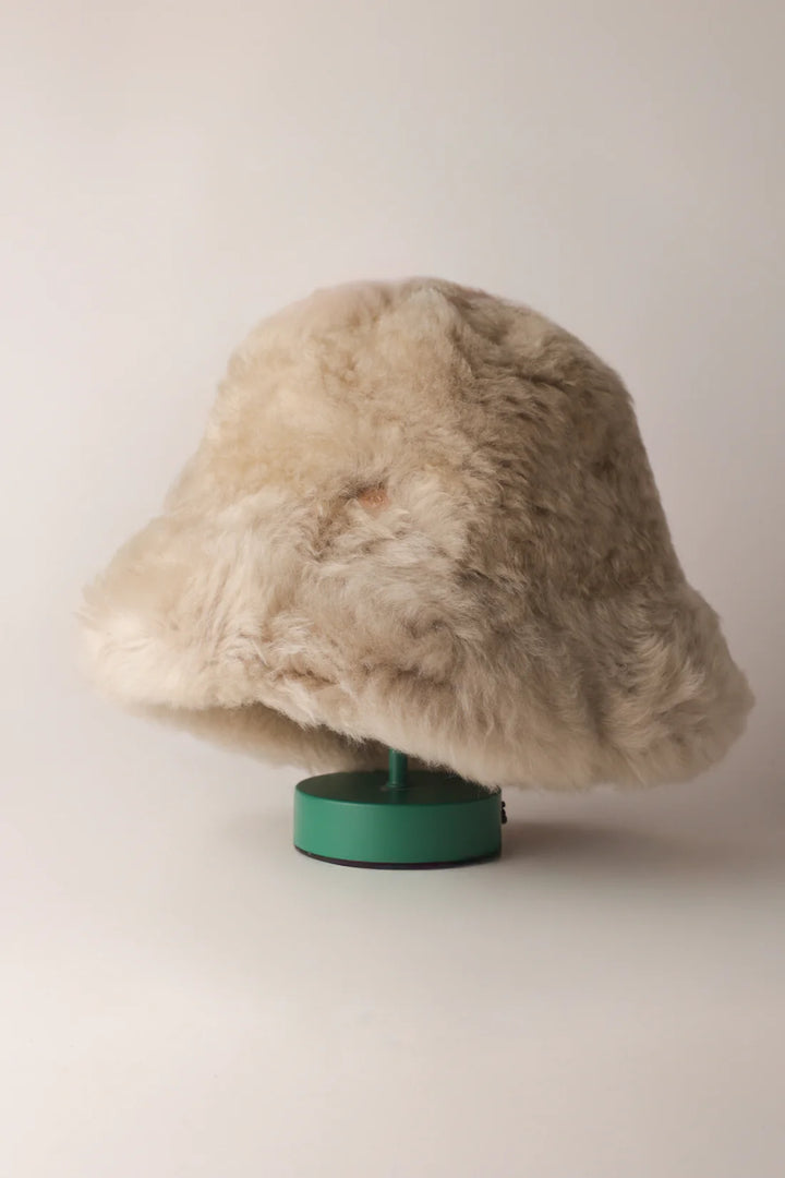 Ljus KYWIE Fluffy-hatt på grönt ställ sedd snett från sidan