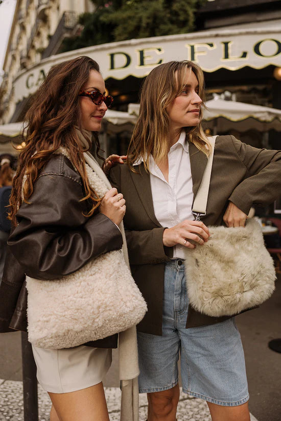 Two people with white KYWIE sheepswool bags outside a café