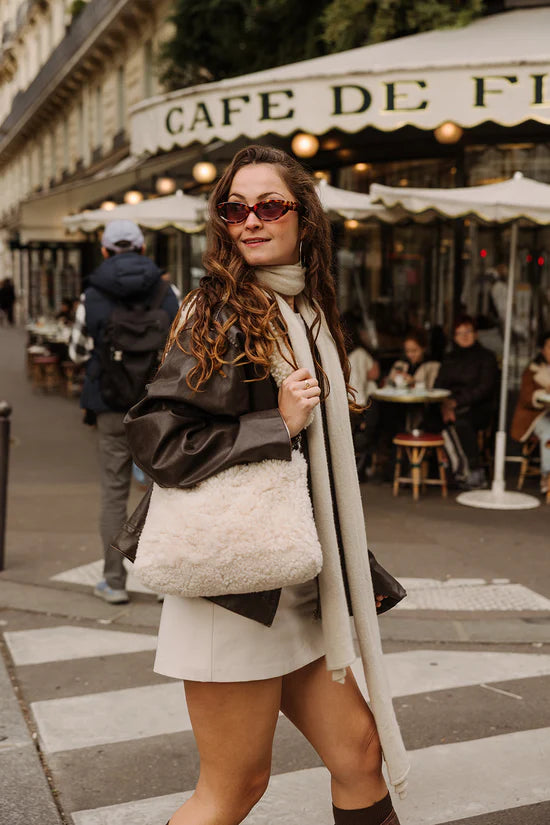 White KYWIE sheepswool bag on a person's shoulder with a dark jacket and light outfit