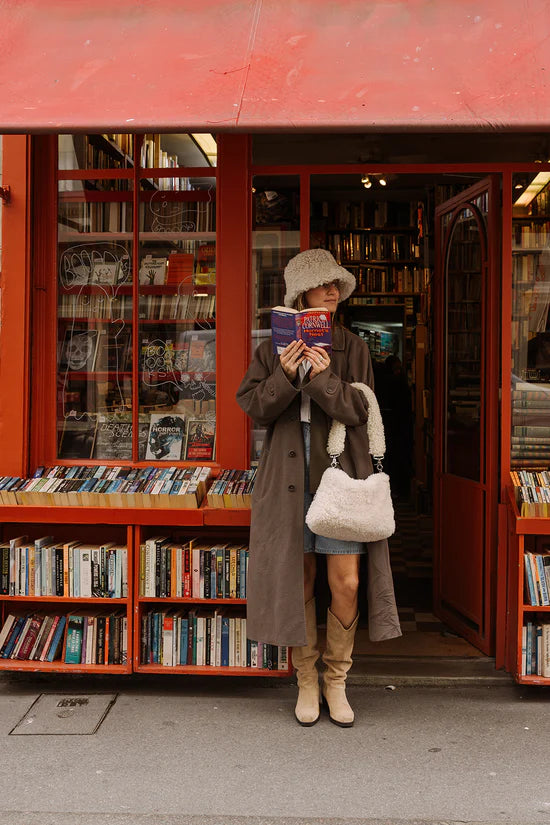 Person carrying a white KYWIE sheepswool bag outside a bookshop