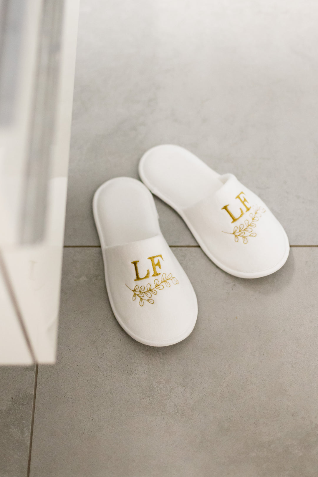 Valkoiset Loffen Hotel Luxus -kylpytossut harmaalla laattalattialla suihkun vieressä