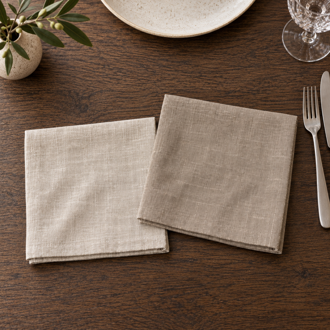 Light and dark No Problem Luxus linen napkins overlapping on a wooden table, viewed from above.