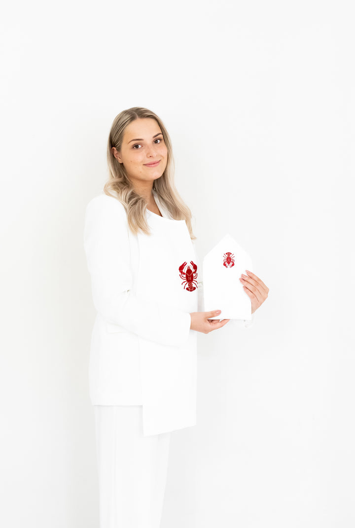 Woman showing a white crayfish bib and matching embroidered napkin