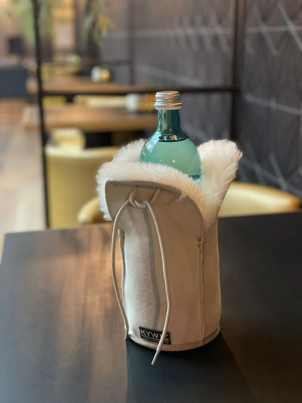 Beige Kywie-pullocooler baaritiskillä, pullo sisällä