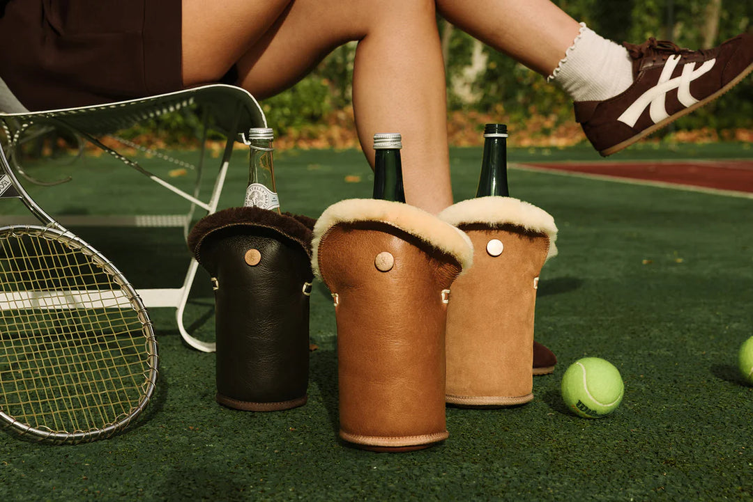 Kolme ruskeaa ja vihreää Kywie-viinicooleria tennismailojen ja pallon vieressä